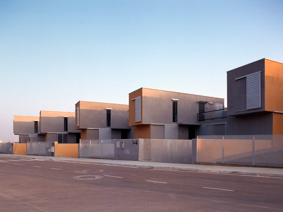 A row of modern, two-story houses with clean lines and minimalist design, featuring large windows and a neutral color palette.