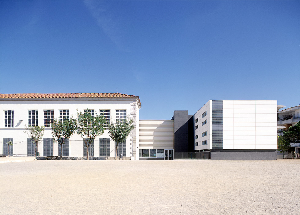 A modern school building with large windows and a spacious courtyard.