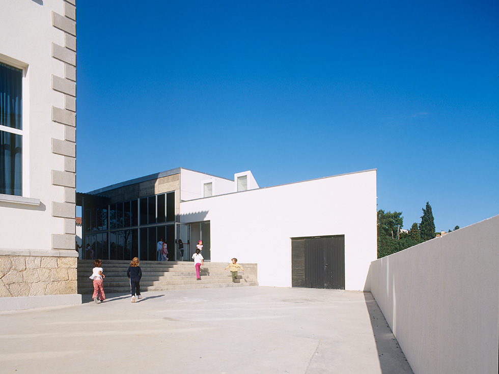 Children playing in the courtyard of a modern school building.