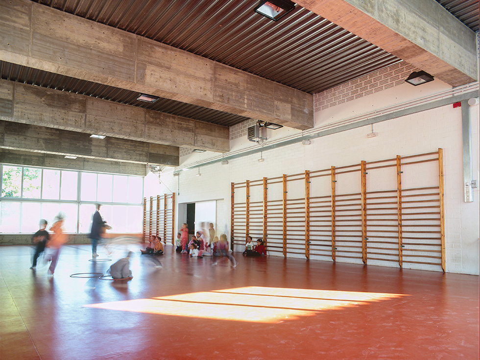 Children playing in a brightly lit school gymnasium.