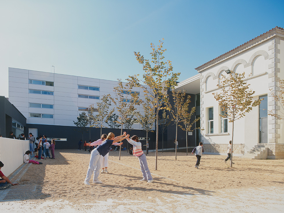 School courtyard with children playing, surrounded by modern and traditional buildings.