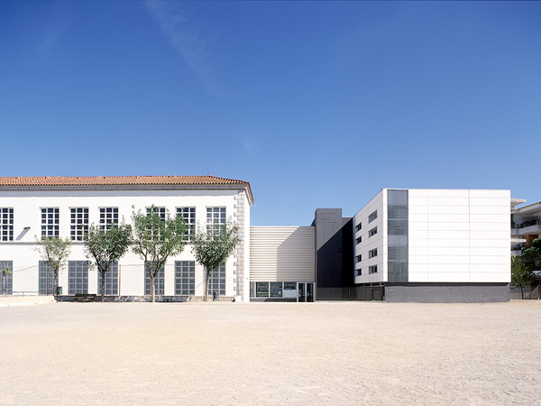 A modern school building with large windows and a spacious courtyard.