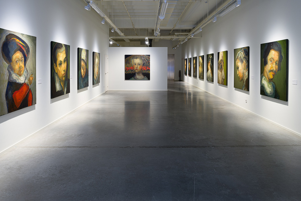 Exhibition hall with large Guerrero Medina's portrait paintings, white walls, and polished concrete floor.