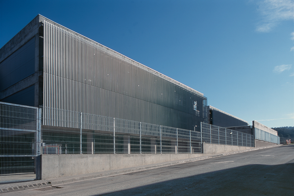 Exterior view featuring a modern design with vertical metal cladding and a secure fence along the perimeter.