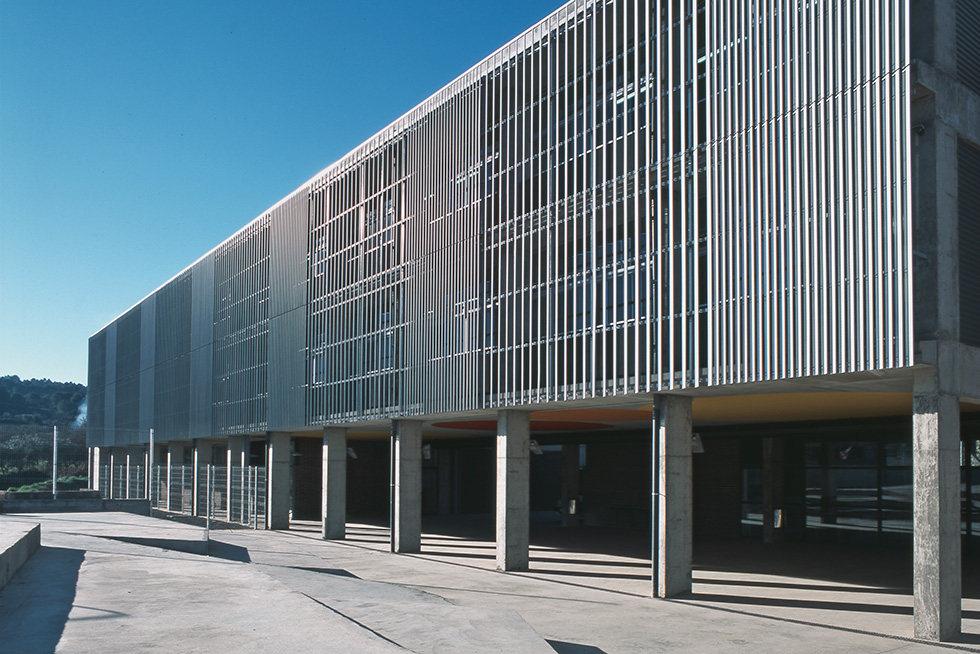 Exterior view featuring a facade with vertical metal slats and concrete columns supporting the structure.