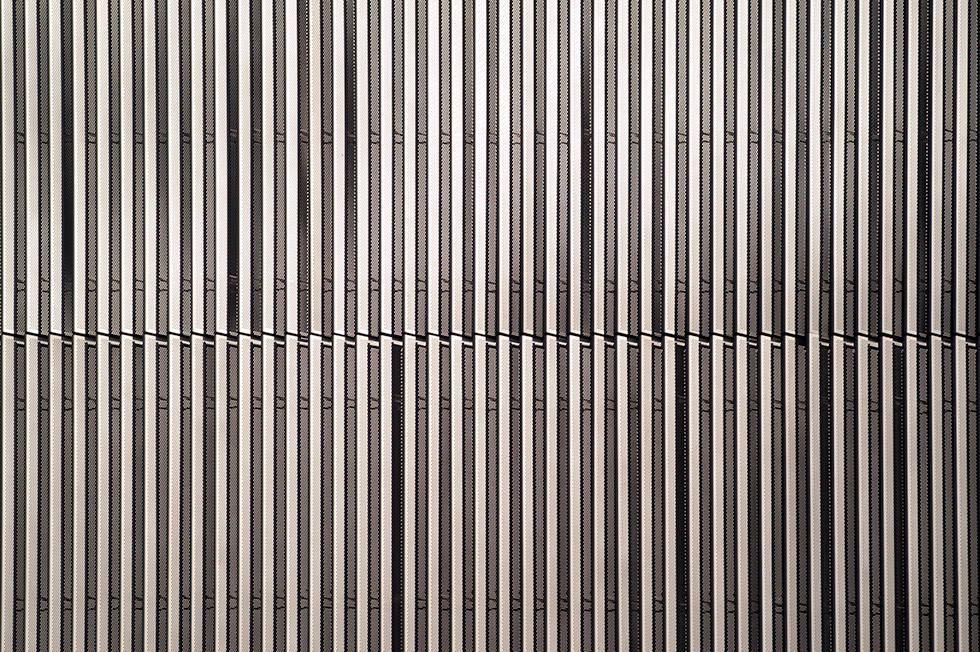 Close-up view of the vertical metal slats forming the facade of Artes High School, creating a dynamic and textured pattern.