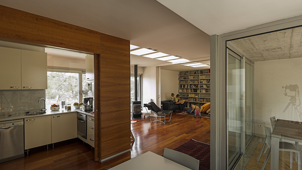 View from the kitchen into the living area, showcasing an open floor plan with wooden floors and a cozy reading nook.