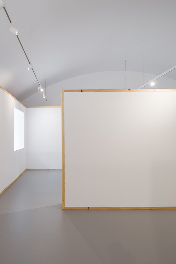 Interior view featuring white partition walls with wooden frames and overhead lighting.