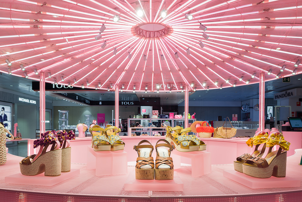 Platform sandals displayed under pink illuminated ceiling in Miu Miu's pop-up store.