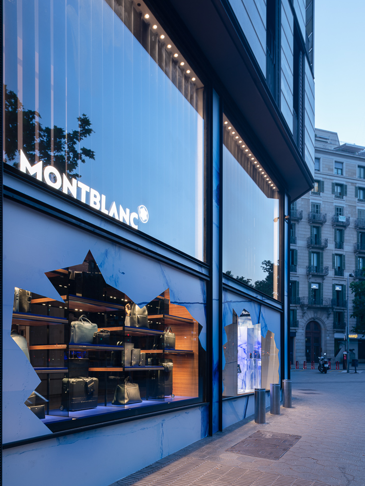 Close-up of Montblanc store's glacier-themed window displays with illuminated shelves showcasing luxury products.