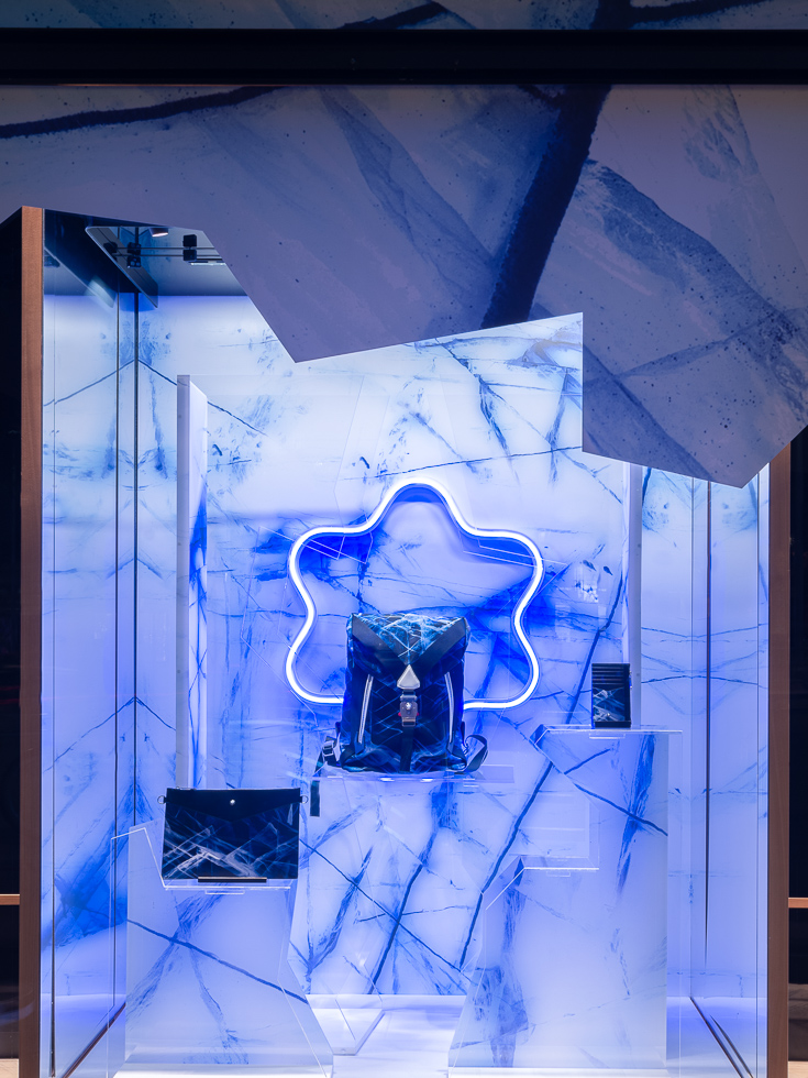 Montblanc store display featuring a blue glacier-themed backdrop with a backpack and writing accessories.