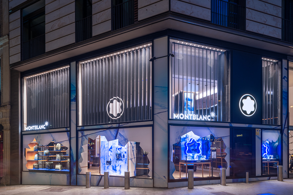 Montblanc store at night showcasing glacier-themed window displays with illuminated accessories and bags.