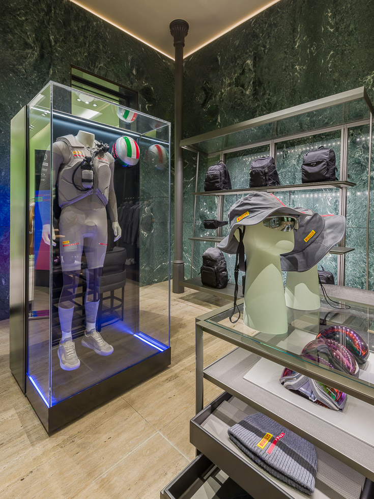 Luxury Prada boutique with green marble walls, showcasing a mannequin in a performance outfit encased in a glass display.