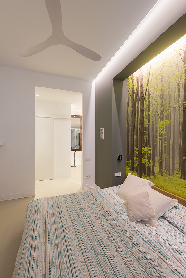 Modern bedroom with forest-themed wallpaper, a ceiling fan, and soft ambient lighting.