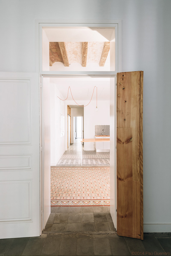 Open door revealing a room with patterned floor tiles and exposed wooden beams on the ceiling.