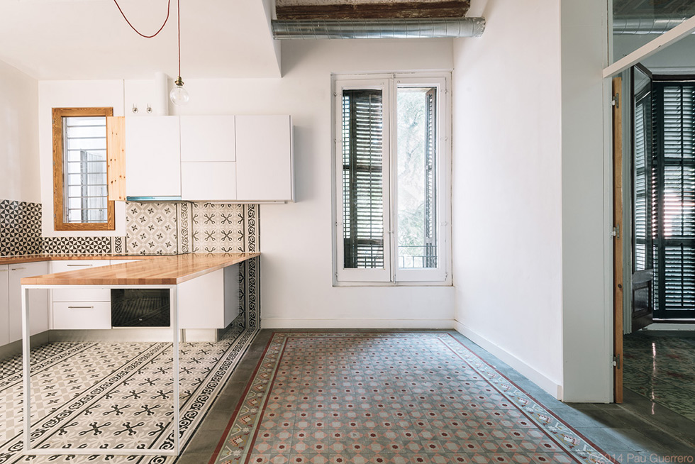 Modern kitchen with patterned tiles, wooden accents, and a minimalist work table.