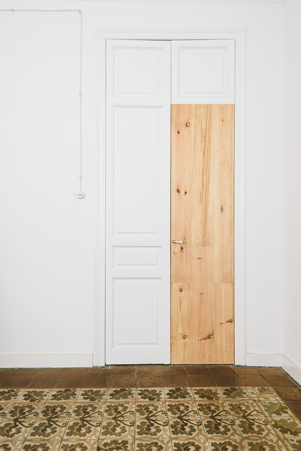 White door with a partially wooden panel and patterned floor tiles.