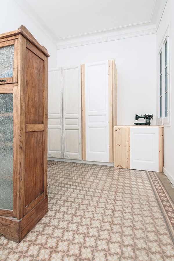 Room with vintage furniture, patterned floor tiles, and a sewing machine on a wooden cabinet.