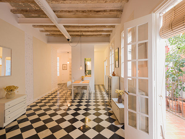 Spacious dining area with checkered floor tiles, exposed beams, and French doors opening to a patio area.