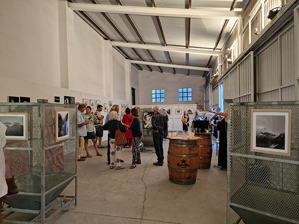 People viewing artwork at an exhibition in an industrial-style gallery space.