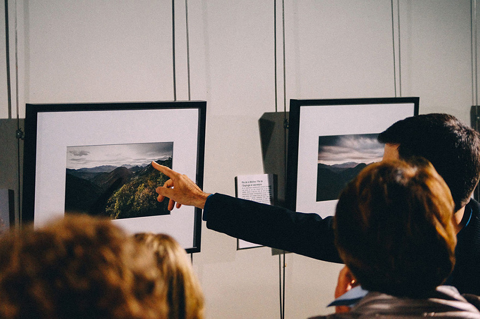 A man pointing at a photograph while explaining it to a group of people.