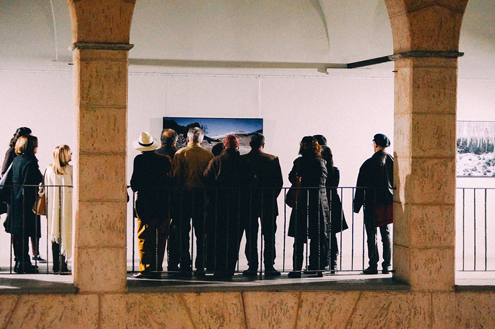 A group of people viewing photographs in an exhibition hall.