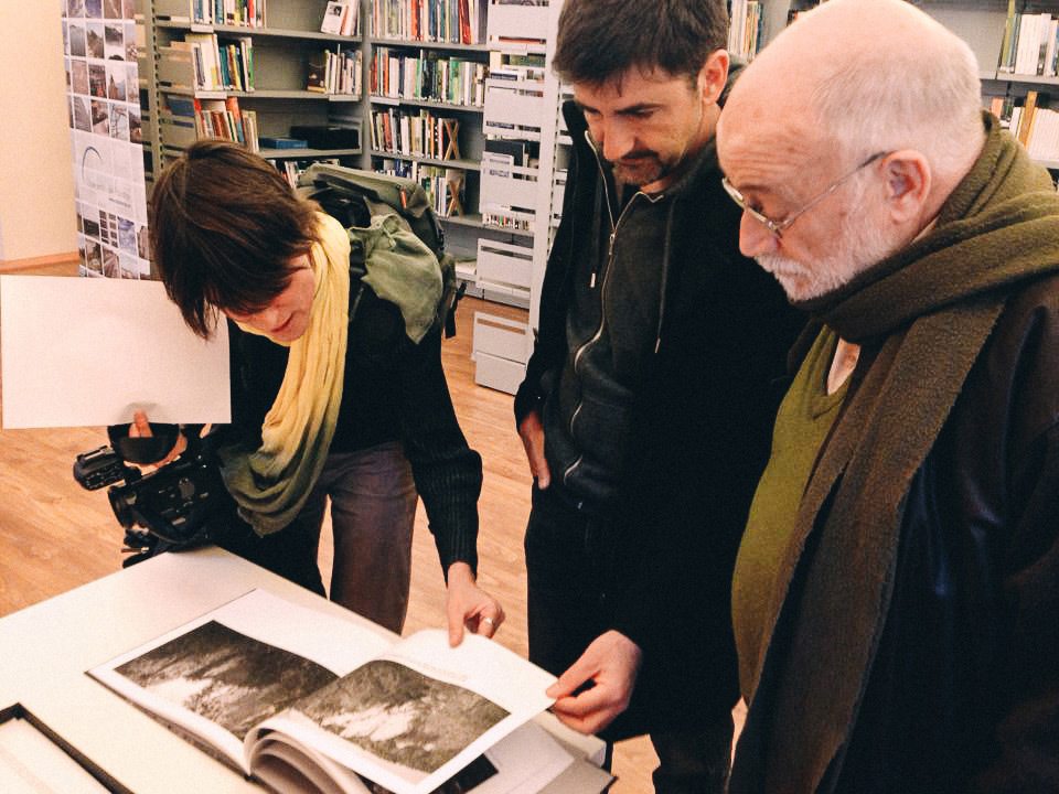 Three people looking at an open book with landscape photographs.