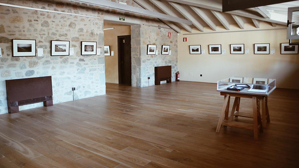 Empty art gallery room with framed photos on stone and plaster walls.