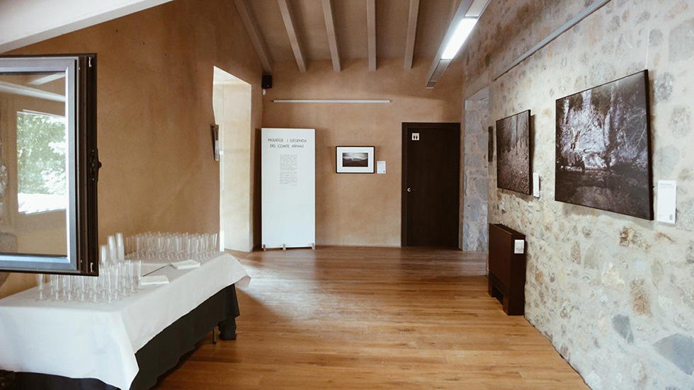 Room with framed photos on stone walls and a table set with glasses for the opening day.