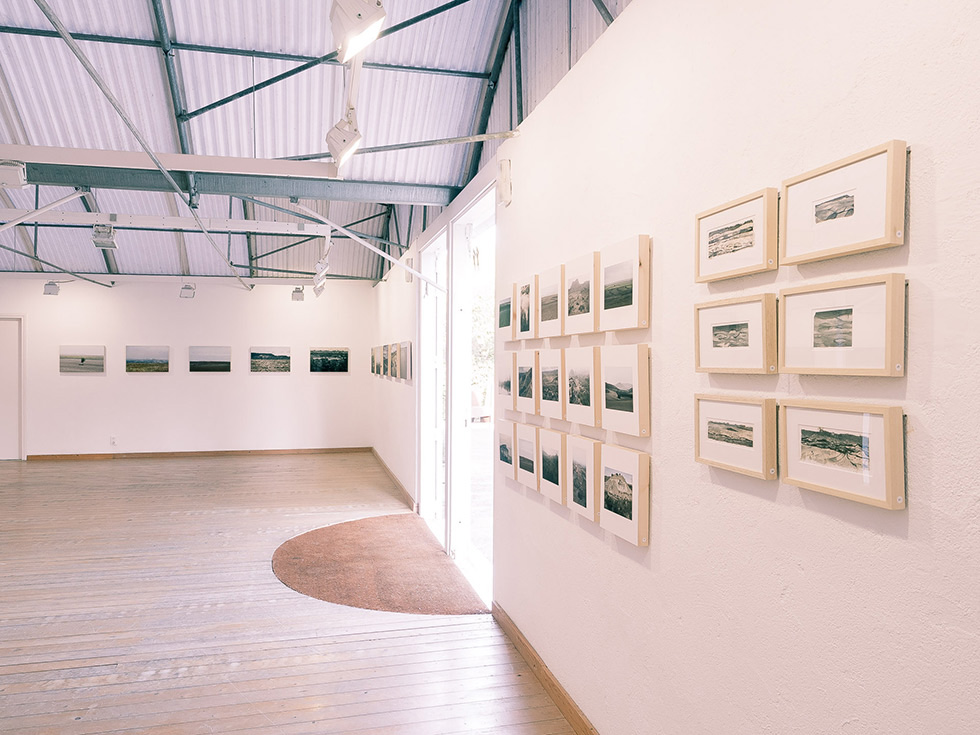 Exhibition space featuring framed artworks on the walls.