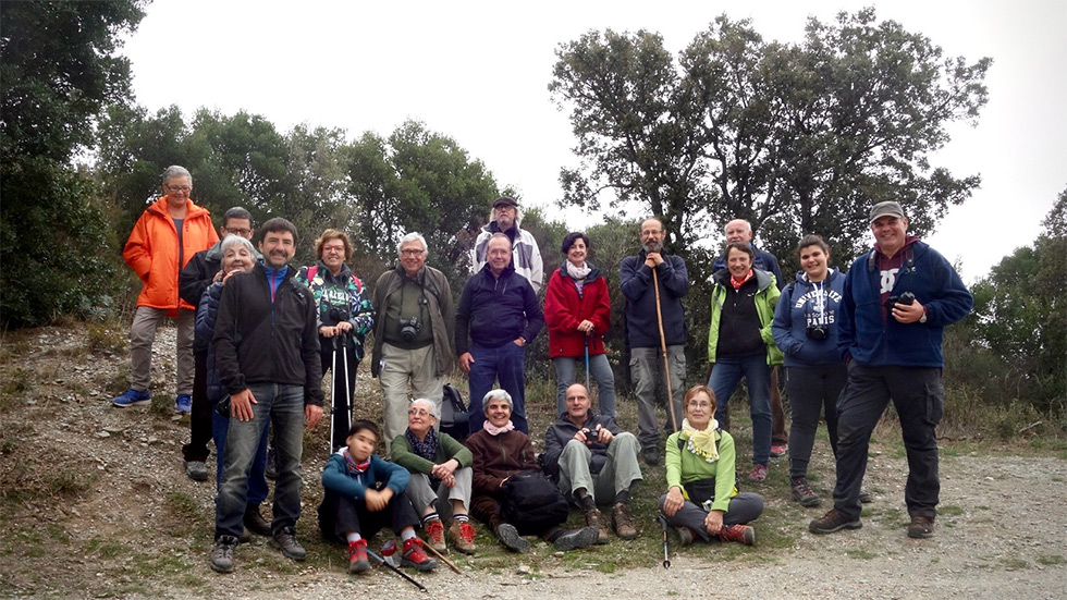 A group of people posing together outdoors on a trail with trees in the background.