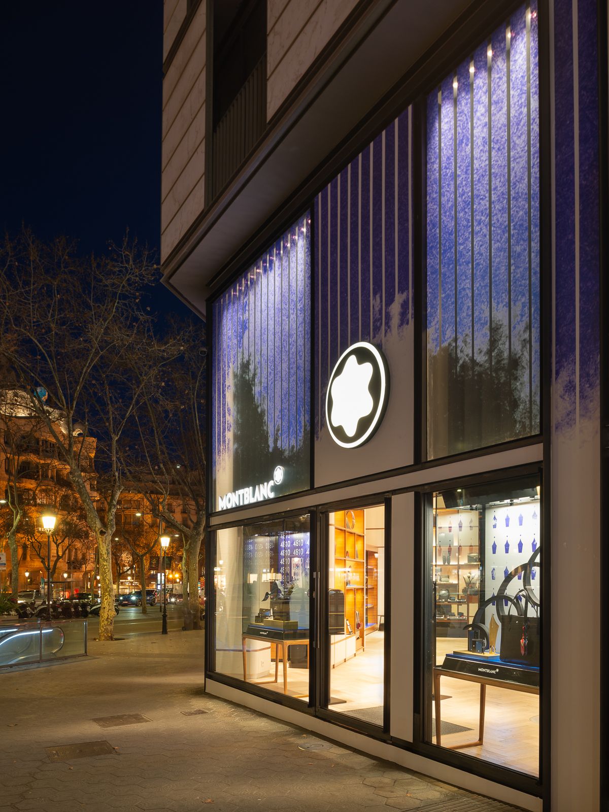 Exterior de tienda Montblanc por la noche, con señalización iluminada y una vista de las elegantes exhibiciones interiores.