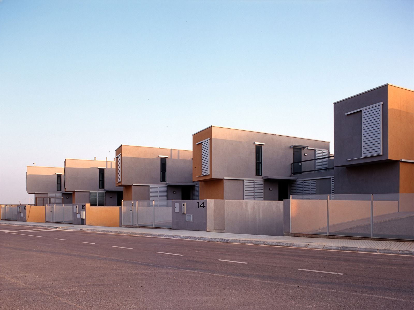 A row of modern, two-story houses with clean lines and minimalist design, featuring large windows and a neutral color palette.