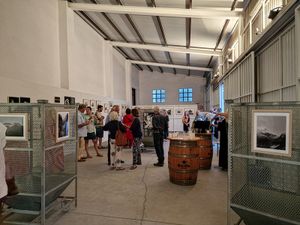 Personas viendo obras de arte en una exposición en un espacio de galería de estilo industrial.