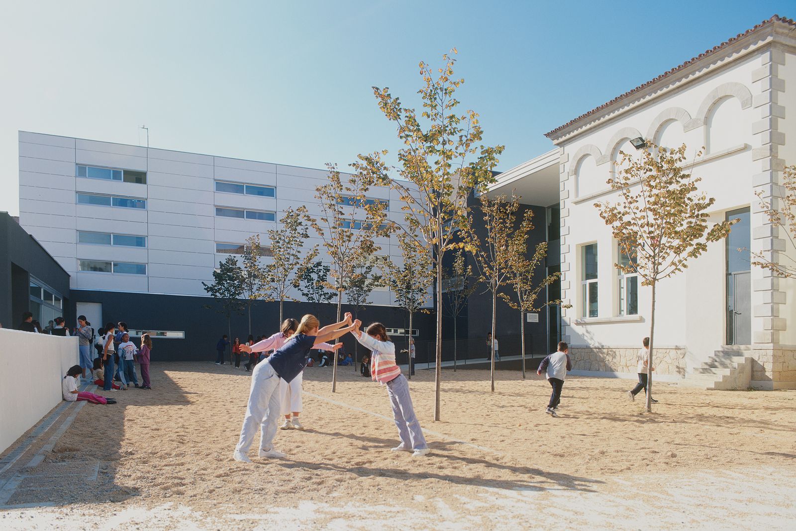 School courtyard with children playing, surrounded by modern and traditional buildings.