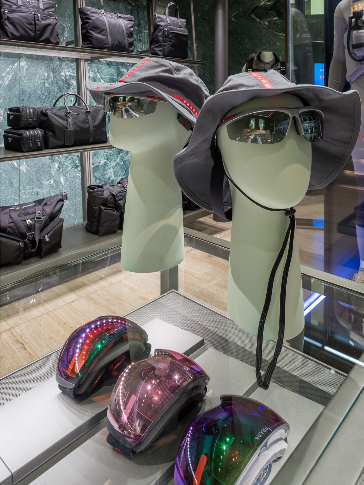 Lujosa boutique Prada, una mesa de vidrio exhibe gafas, sombreros y gafas de esquí de rendimiento.