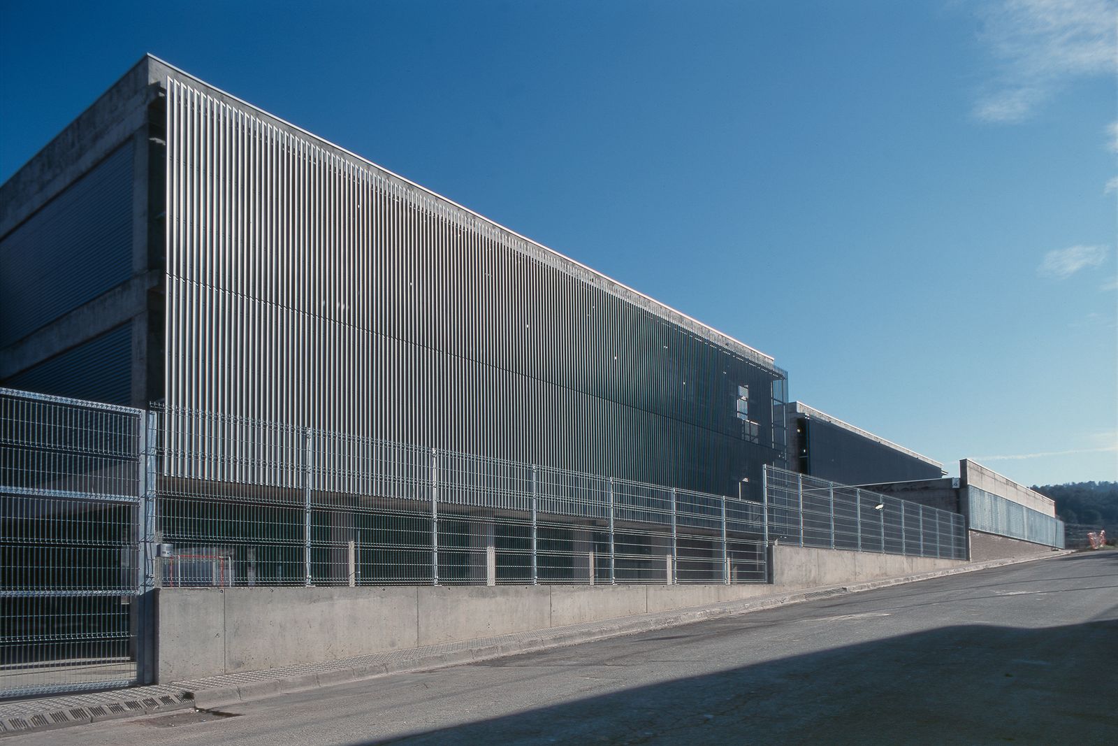 Exterior view featuring a modern design with vertical metal cladding and a secure fence along the perimeter.