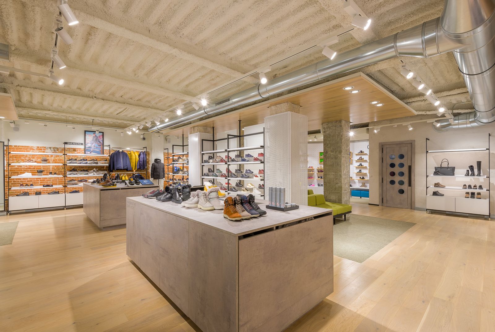 Interior de la tienda Geox, mostrando un espacio moderno y bien iluminado con zapatos y chaquetas ordenadamente exhibidos en estantes y mesas.