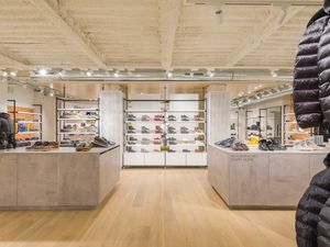 Interior de la botiga Geox a Barcelona, mostrant un espai modern i ben il·luminat amb sabates i jaquetes exposades ordenadament en prestatges i taules.