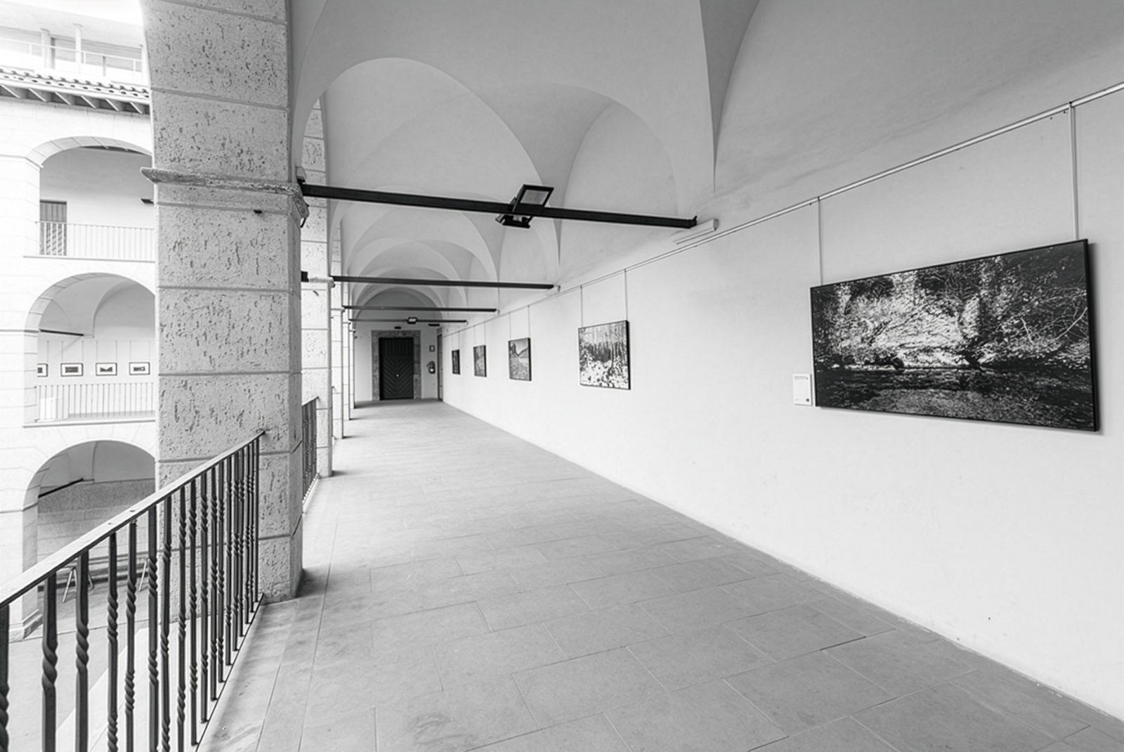 Pasillo cubierto en una galería de arte con fotografías expuestas en las paredes.