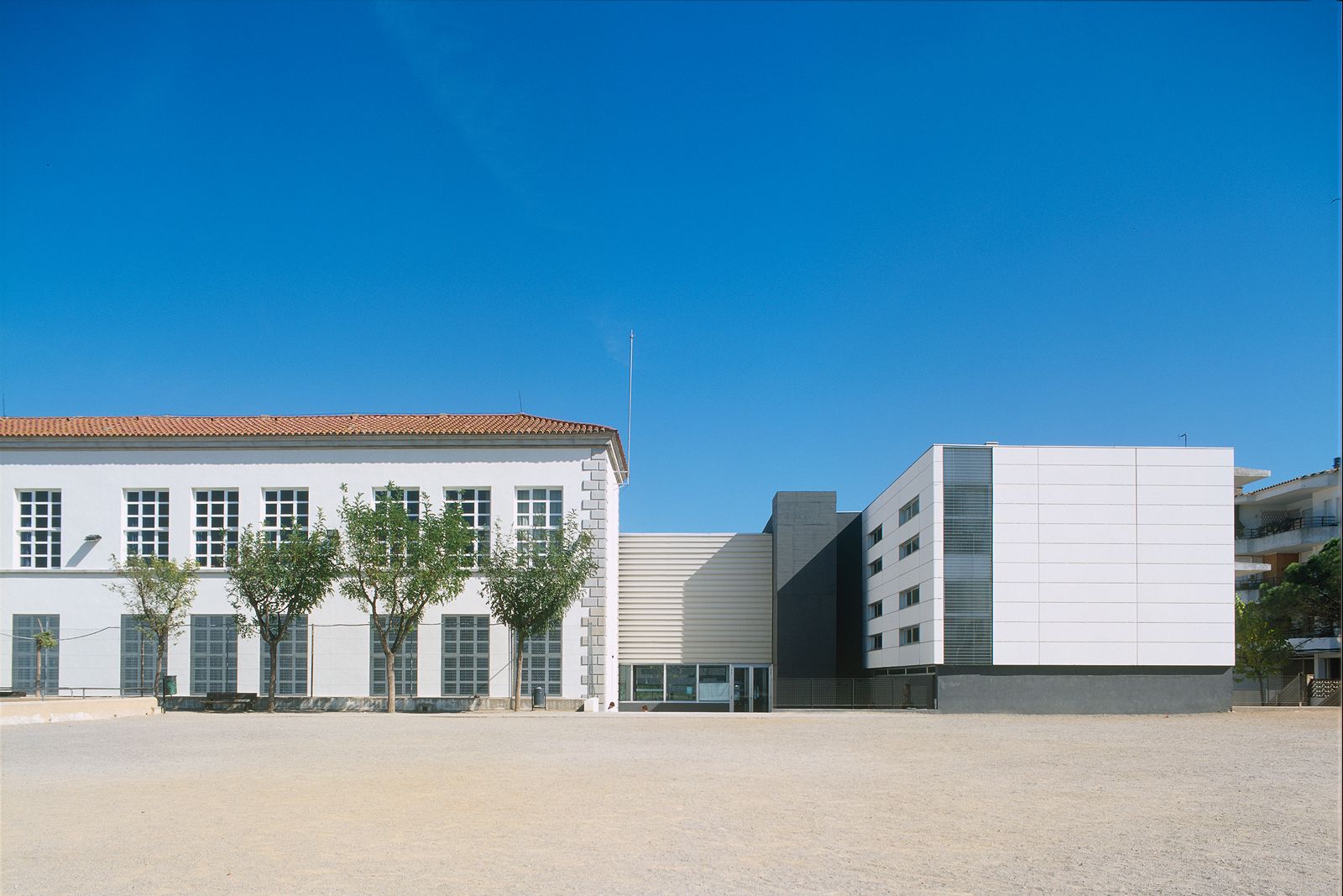 A modern school building with large windows and a spacious courtyard.