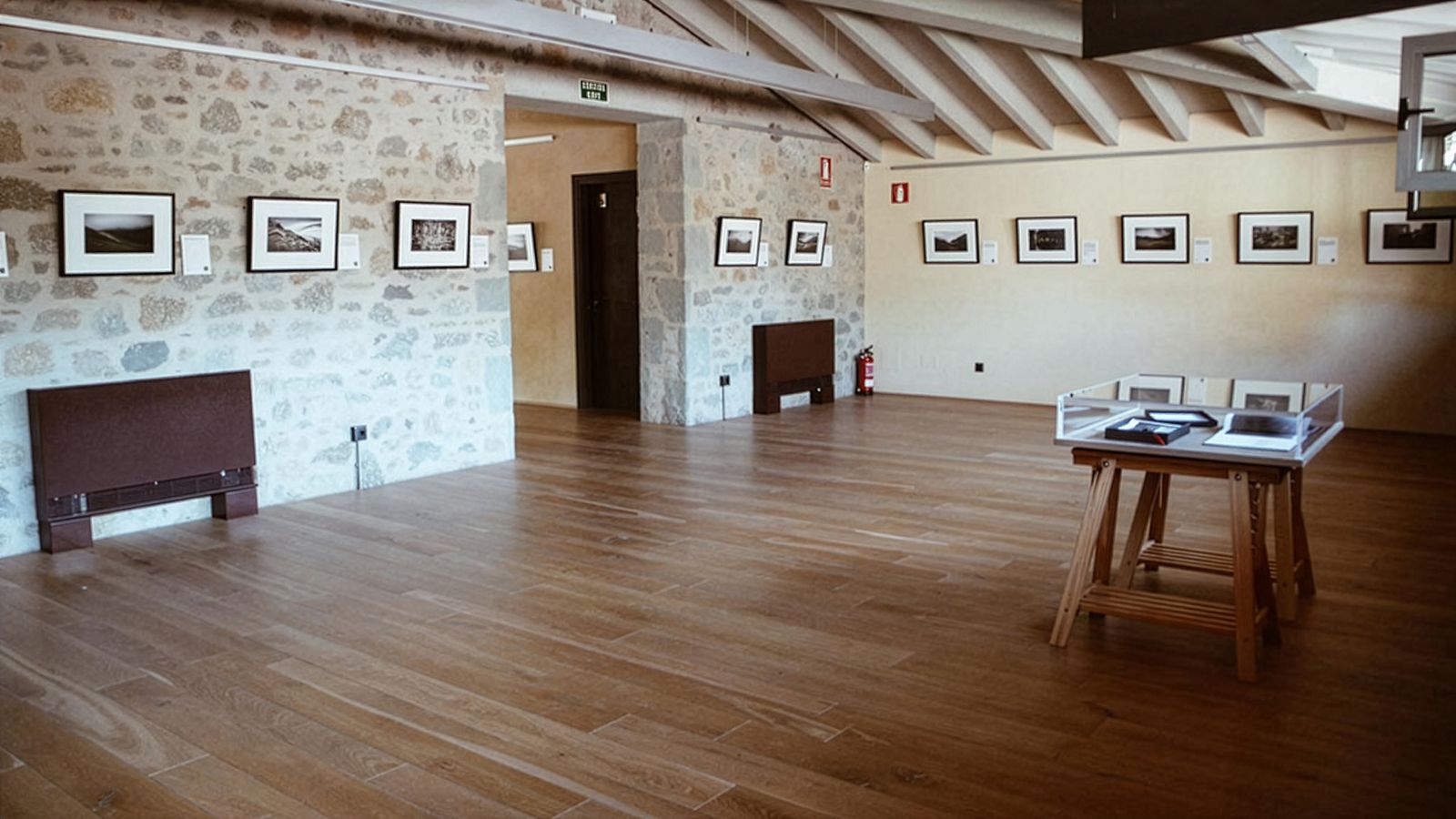 Sala de galería de arte vacía con fotos enmarcadas en paredes de piedra y yeso.