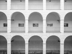 Els arcs del claustre de l'antic Hospici d'Olot amb unes fotografies de gran format al darrera.