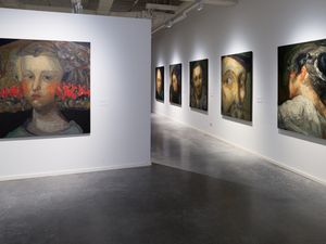 Galeria d'art amb pintures de retrats de Guerrero Medina exposades, amb un gran retrat destacat en una paret divisòria blanca.