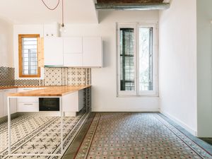 Cuina moderna amb rajoles amb patrons, accents de fusta i una taula de treball minimalista.