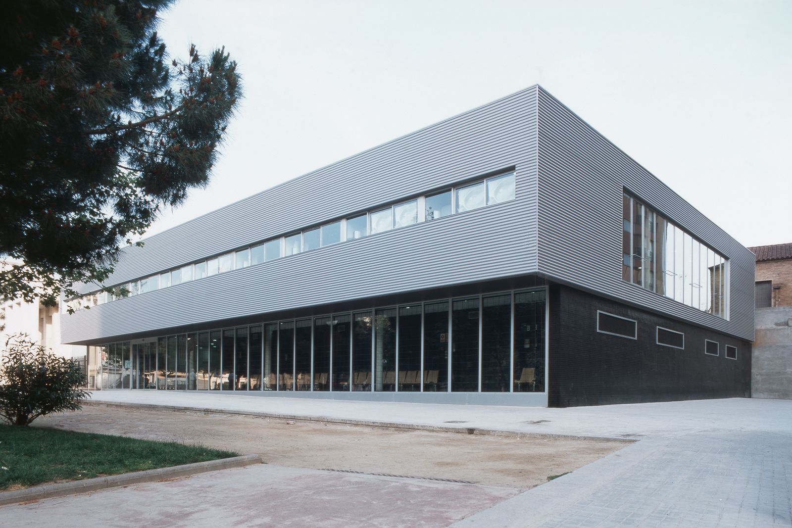 A modern medical clinic exterior featuring large windows and sleek, horizontal metal paneling.